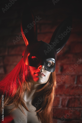 Female mannequin face in rabbit mask close up on the neon lights background. Beauty and fashion.
