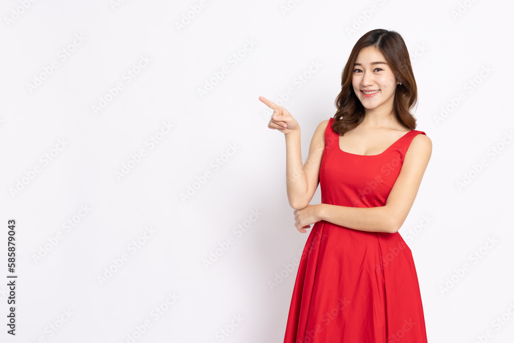 Young elegant beautiful Asian woman in red dress smiling and pointing to empty copy space isolated on white background Young elegant beautiful Asian woman in red dress smiling and pointing to empty copy space isolated on white background