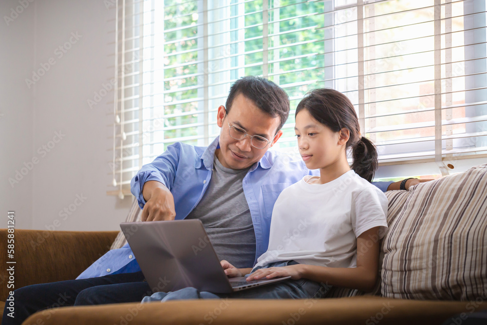 Asian father and daughter using laptop at home, People doing activities and family concepts Asian father and daughter using laptop at home, People doing activities and family concepts