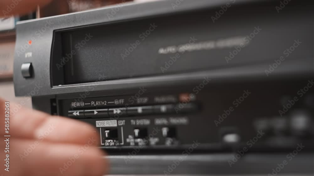 Male hand pulls out VHS from a vintage videotape recorder. Eject VHS