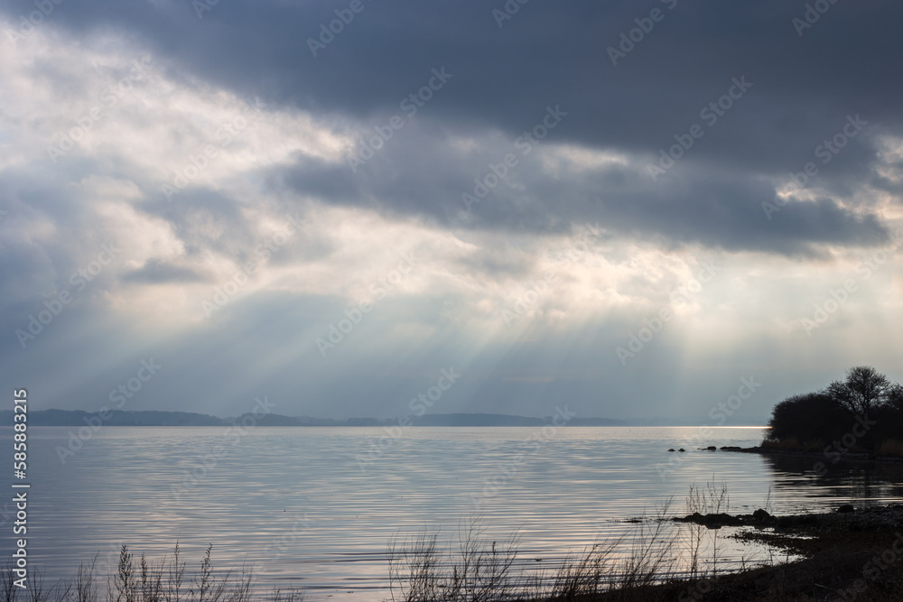 Mystic scenery with sun rays breaking through the clouds at the fjord