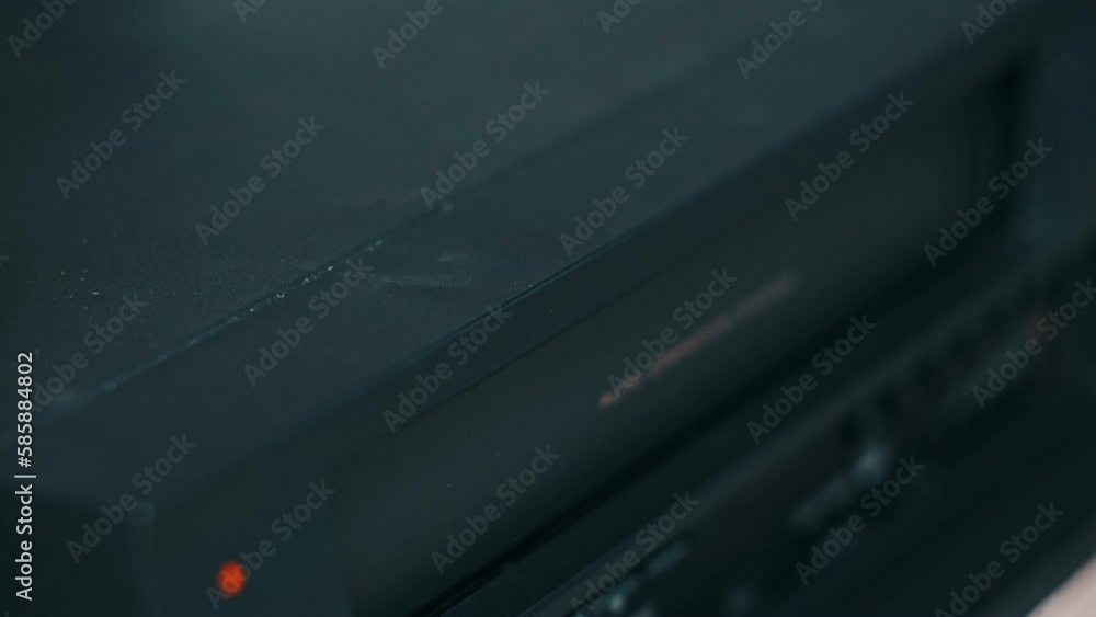 Eject VHS tape cassette from VCR player. Male hand pushes a button and