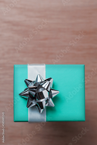 Turquoise blue gift box with silver bow and white ribbon. Copy space available