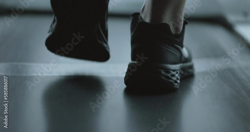 Side view legs in sneakers walk on treadmill in fitness gym unknown woman and man going footstep sport people runners walk on running machine slow stride foot step pace cardio workout health lifestyle photo