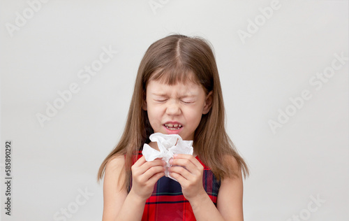 Child going to sneeze into napkin in hands showing allergic rhinitis or cold on white background