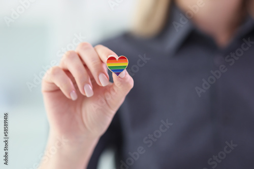 Woman holding small heart with LGBT flag colors closeup photo