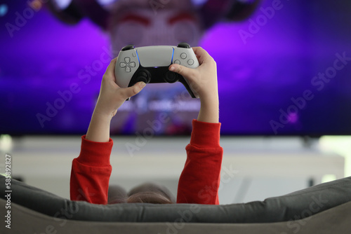 Hands of little girl holding game console against screen