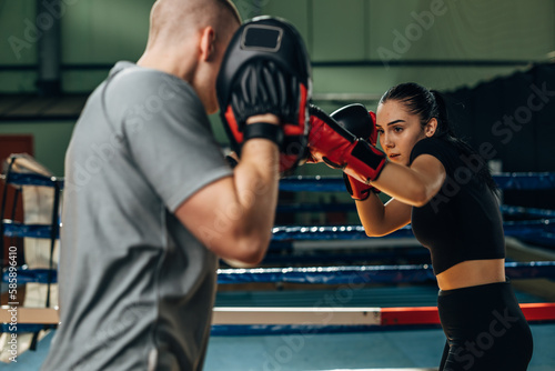 Canvas Print A young woman is working on punches with her instructor