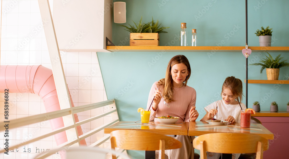Mother and daughter having a breakfast with fresh squeezed juices in the cafe Mother and daughter having a breakfast with fresh squeezed juices in the cafe