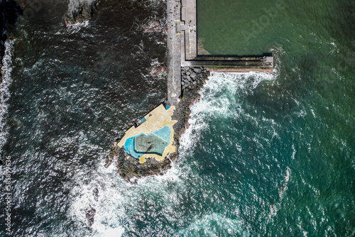 Drone view of the Caloura natural swimming pool, located in a seaside fishing village with great views and a secluded beach in the Sao Miguel island in the Azores, Portugal