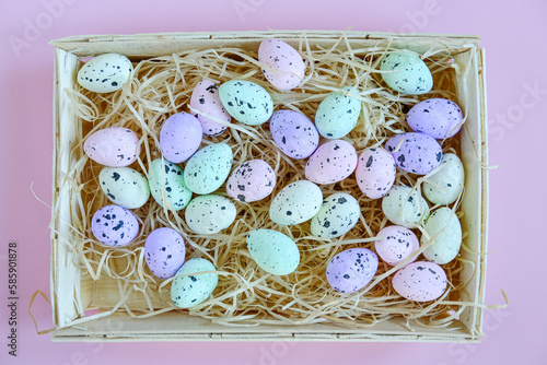 Basket of colored Easter eggs on a pink background. View from above. Place for text