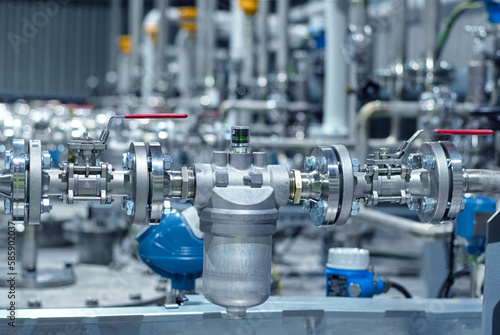 An stainless steel instalation. A new hydraulic filter with new ball valves installed in an additive pumping station with pipelines on the background. Industrial area. Industrial application.