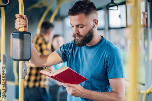 Man reading a book while riding in a bus