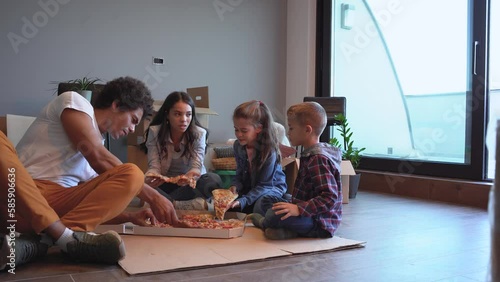 Mixed race family moving into their new home. They're taking a break and eating pizza after unpacking.	
