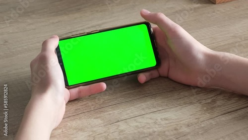A man is holding a phone with a green screen. Online training. Communication online. phone in hand