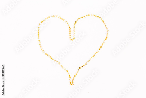 heart made of long golden beads on a white background