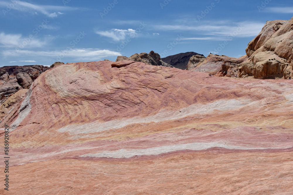 Fototapeta premium Amazing colors and massive formations around the Fire Wave rock in Valley of Fire State Park, Nevada, USA. Pink and red pastel colors of the sandstone and blue sky in the background