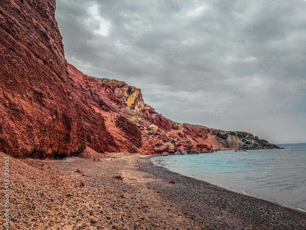 The famous Red Beach, Kokkini Paralia in Santorini island, Greece. Unique red sand beach on a cloudy day The famous Red Beach, Kokkini Paralia in Santorini island, Greece. Unique red sand beach on a cloudy day