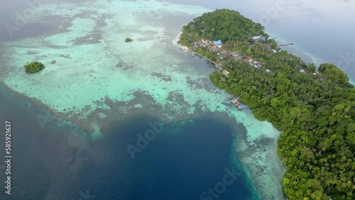 Aerial Footage. Small village on a tropical island with huge shallow reef in crystal clear water photo