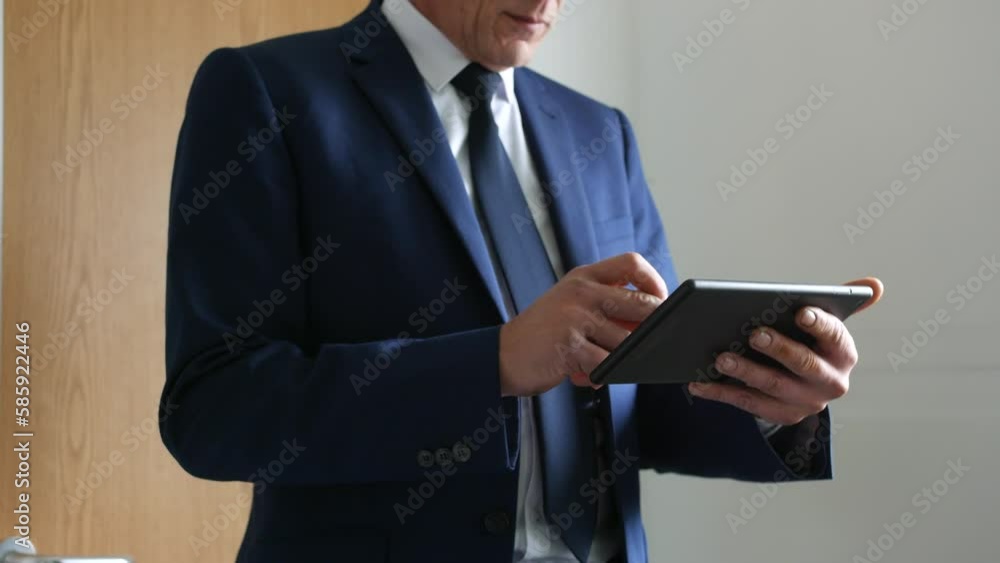 an unrecognizable business man using a tablet computer at work outside his office wearing a suit and tie an unrecognizable business man using a tablet computer at work outside his office wearing a suit and tie