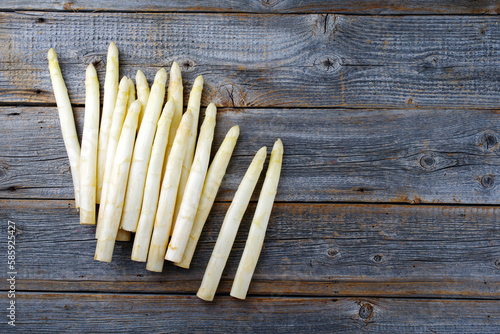 Frischer roher weißer Spargel angeboten als close-up auf einem gebleichten grauen Holz Board mit Textfreiraum