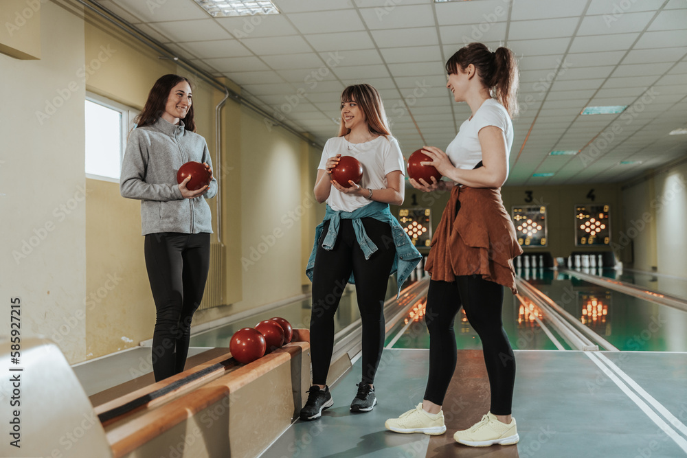 Fototapeta premium Three Female Friends Having Fun And Bowling Together