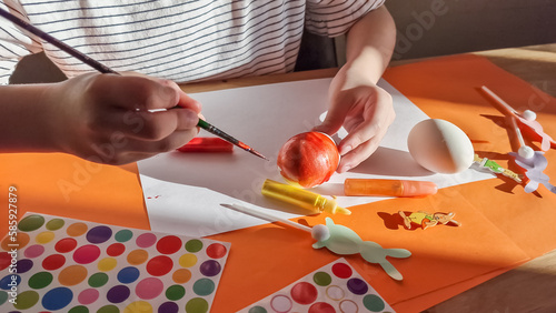 little girl painting eggs for Easter at home, in kindergaten or preschool. Celebrating holidays with children. Creative activities and games for kids. Stay at home entertainment photo