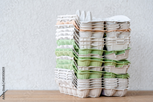 Pile of Empty brown, green and orange paper pulp egg trays, Stack cardboard packaging for eggs, reusable zero waste concept photo