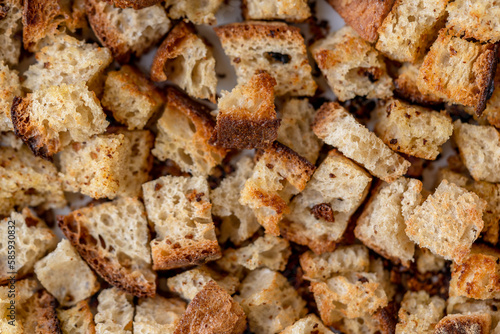 Crispy cubes of bread, croutons of white bread for cream soups. Food texture background of sourdough wheat bread with olive oil and garlic. Recycling zero waste concept