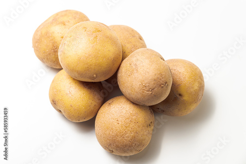 A close up photograph of a pile of yellow and brown russet potatoes from above with white background and copy space.