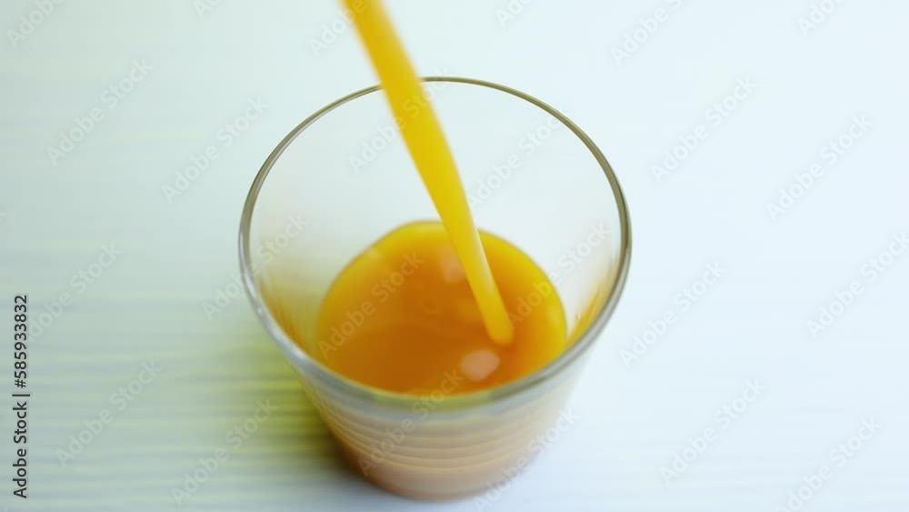 A slow-motion shot of pouring fresh mango juice into a glass. Selective focus. A slow-motion shot of pouring fresh mango juice into a glass. Selective focus.