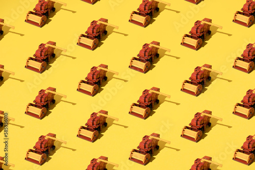 Metal toy harvester on a yellow background. Pattern.