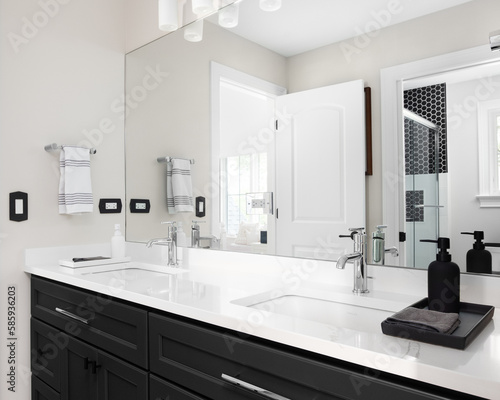 A bathroom with a black cabinet  white marble countertop with two sinks  and a view of the shower in the reflection.
