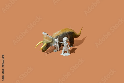 Native Indian American chief leader standing next to a large triceratops dinosaur beast on a brown background.