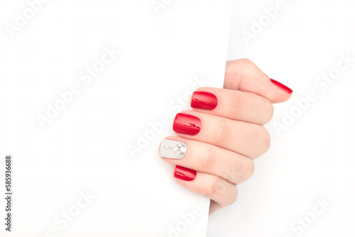 Female hand wih perfect manicure holding white paper corner. Template for postcard, advertising banner or message.