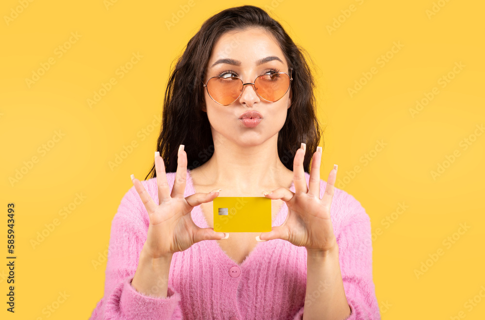 Happy young caucasian brunette woman in glasses showing credit card and looking at empty space Happy young caucasian brunette woman in glasses showing credit card and looking at empty space