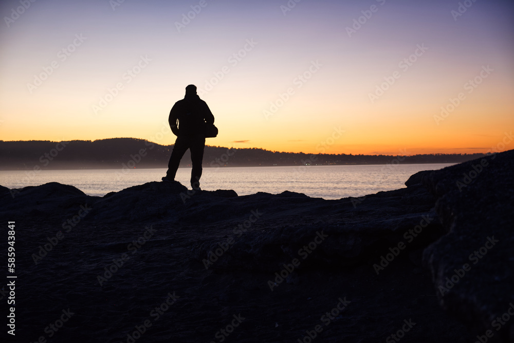 The man at sunset on the background to the ocean coast 