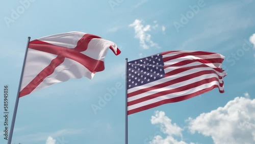 Alabama flag and the USA on a flagpole realistic wave on strong wind in blue sky. State of Alabama and The United States of America