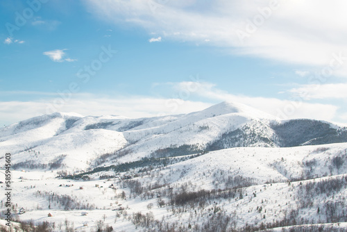 High mountain landscape under the snow with sun and clouds on blue sky © Maja 