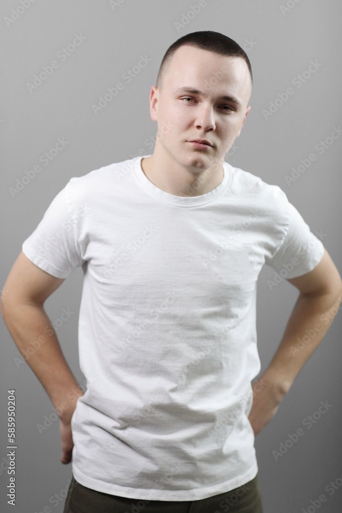 Studio portrait of handsome confident young man in casual white t shirts with mock up crossed his hands and looking at camera isolated on grey background. Studio portrait of handsome confident young man in casual white t shirts with mock up crossed his hands and looking at camera isolated on grey background.
