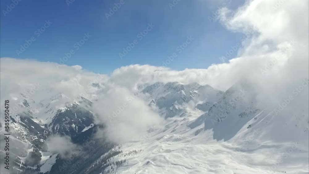 High in the Alps, a snowy mountainside and clouds at the peaks - aerial High in the Alps, a snowy mountainside and clouds at the peaks - aerial