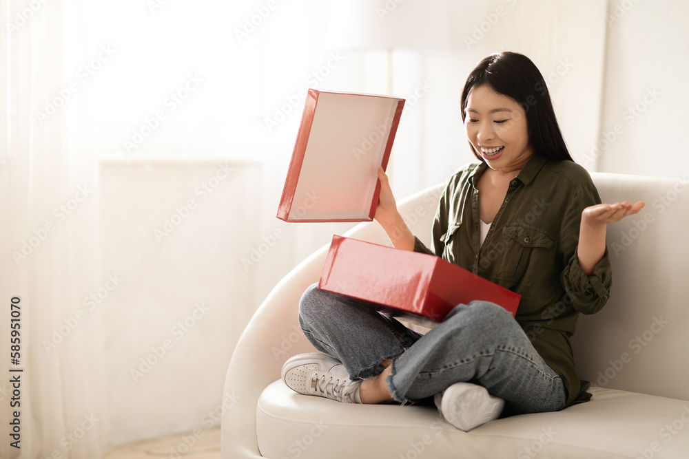 Excited chinese woman looking inside red box, home interior Excited chinese woman looking inside red box, home interior