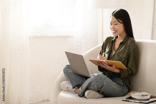 Happy asian woman student attending webinar, using laptop © Prostock-studio