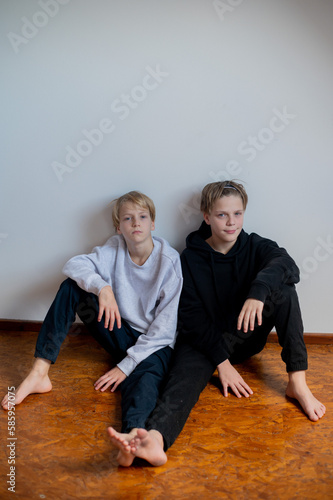 Two happy boys, happy brothers who are seriosly happily together. Brothers stay on grey background. modern tenagers.book cover. one boy in focus other out of focus