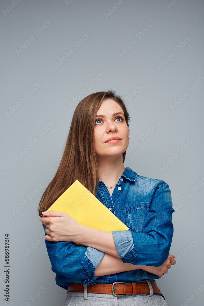 Serious woman student in blue shirt holding yellow book, looking away. Serious woman student in blue shirt holding yellow book, looking away.