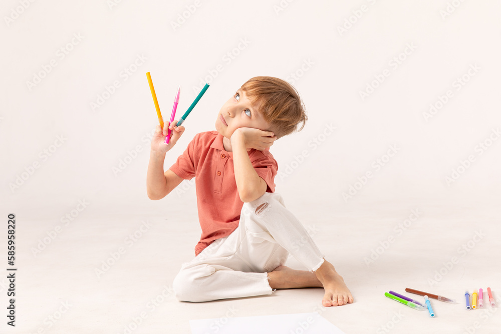 A handsome thoughtful boy sits at the floor on white background and thinks about the answer. Preschool education. A handsome thoughtful boy sits at the floor on white background and thinks about the answer. Preschool education.