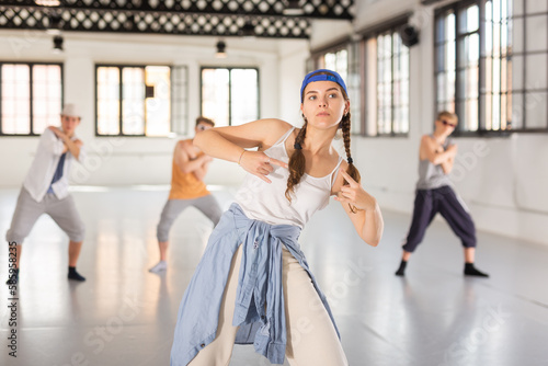 Emotional teenage girl dancer having hip-hop group training at dance hall