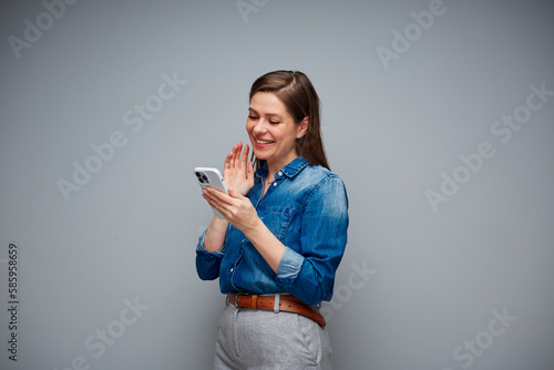 Woman using smartphone for video call. Portrait of smiling girl on gray back.