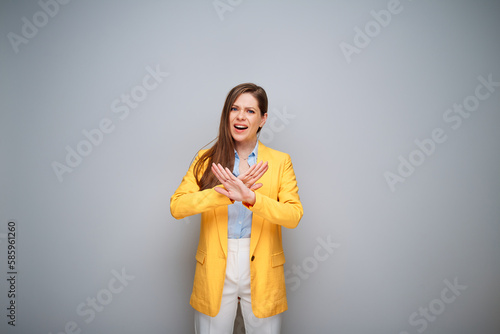 Excited woman in yellow jacket doing stop gest with crossed hands, portrait on gray background photo