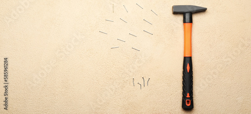 Builder's hammer with nails on light background with space for text photo